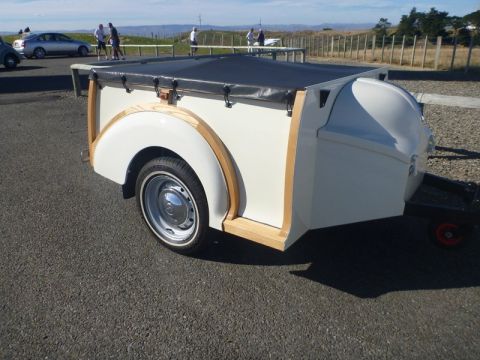 1969 MINI Cooper - A white trailer with a black canvas cover and wooden trim is parked outdoors on an asphalt surface.