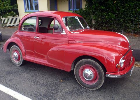 1969 MINI Cooper - This red classic car, likely a Morris Minor, is captured from a 3/4 front angle.