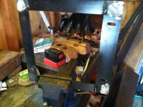 1992 Ford C-350 (Centurion Conversions) - A metal frame is secured in a vise, with various engine components visible in the cluttered background.
