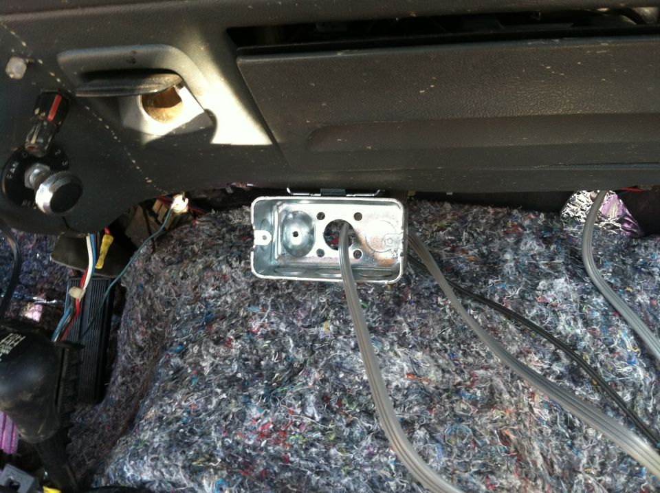 Interior view of vehicle wiring and an electrical box mounted under the dash