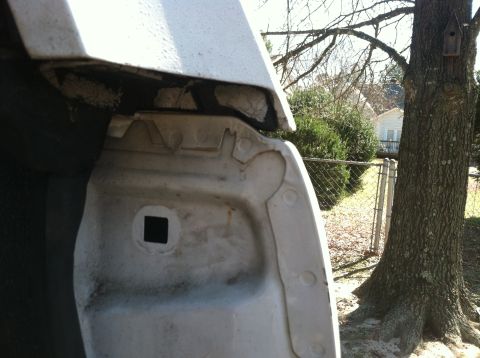 1992 Ford C-350 (Centurion Conversions) - The underside of a vehicle's fender well is visible, with a tree and house in the background.