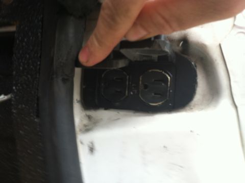 1992 Ford C-350 (Centurion Conversions) - Two electrical outlets are visible on a white surface, with a finger interacting with the left one.