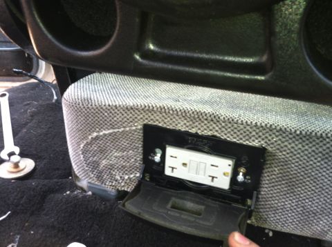 1992 Ford C-350 (Centurion Conversions) - A wrench lies on the carpeted floor near a modified power outlet installed in the vehicle's interior.