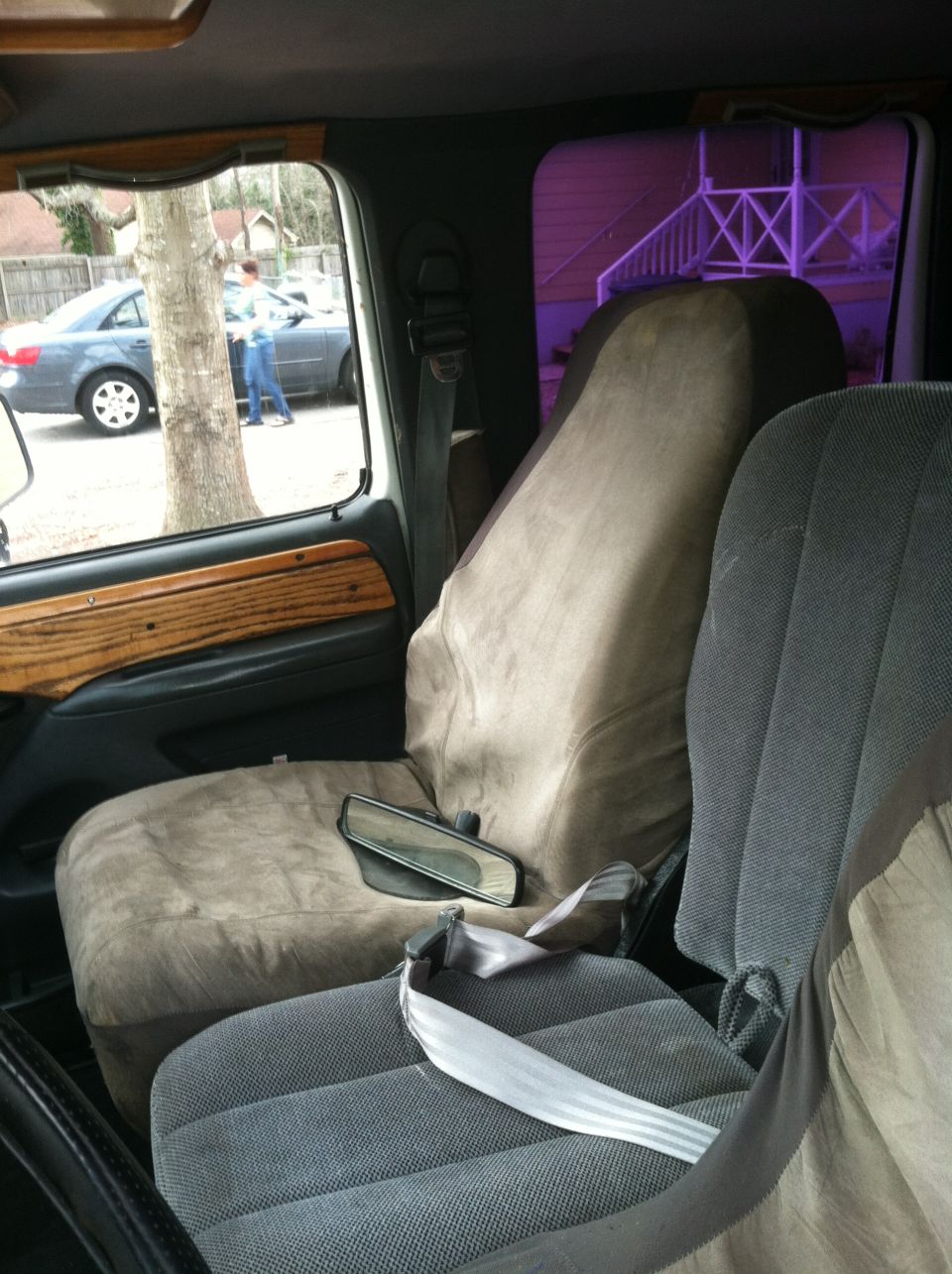 Truck cab interior with gray cloth and tan-covered seats, woodgrain door trim, loose rearview mirror