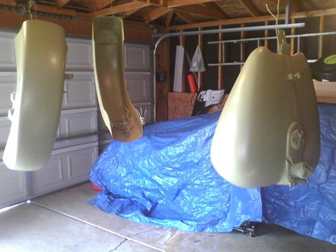 2003 Ford Crown Victoria - Car parts are suspended in a garage, possibly for painting or repair, over a blue tarp.