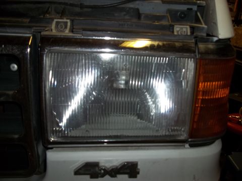1990 Ford Bronco - Close-up of the front headlight and 4x4 badge on a 1990 Ford Bronco.