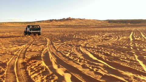 1994 Ford Bronco - A Ford Bronco navigates sandy terrain, leaving tire tracks behind.