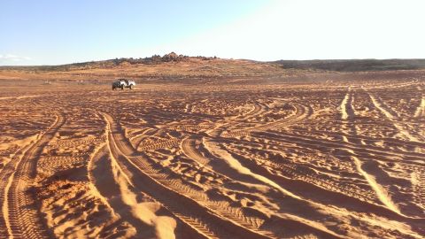 1994 Ford Bronco - A single vehicle navigates a vast desert landscape under a clear sky.