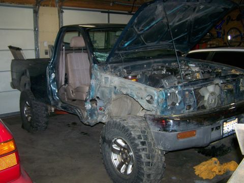 1988 Suzuki Samurai - This pickup truck is in a garage with its hood open and missing body panels.