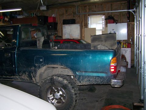 1988 Suzuki Samurai - Rear view of a teal pickup truck parked inside a garage, with another vehicle visible in the background.