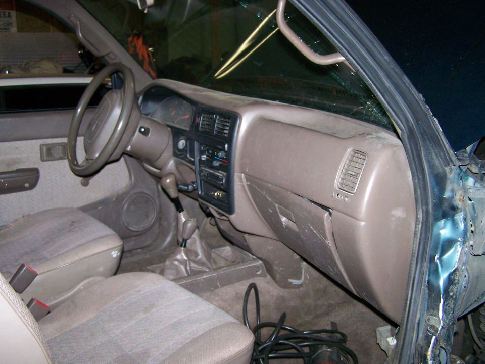 Interior view of a pickup truck dashboard and seats, showing a manual transmission shifter