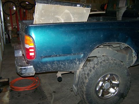 1988 Suzuki Samurai - Teal pickup truck rear quarter panel with a large radiator in the bed.