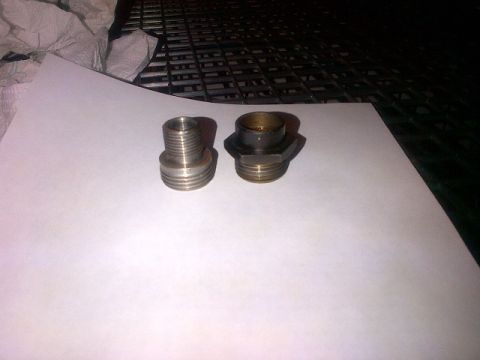 1994 Ford Bronco - Two metal threaded fittings are shown on a white surface, with a dark grate in the background.