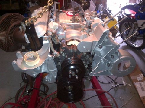 1994 Ford Bronco - Engine assembly with various components, including pulleys and a fan, mounted on a stand in a workshop setting.