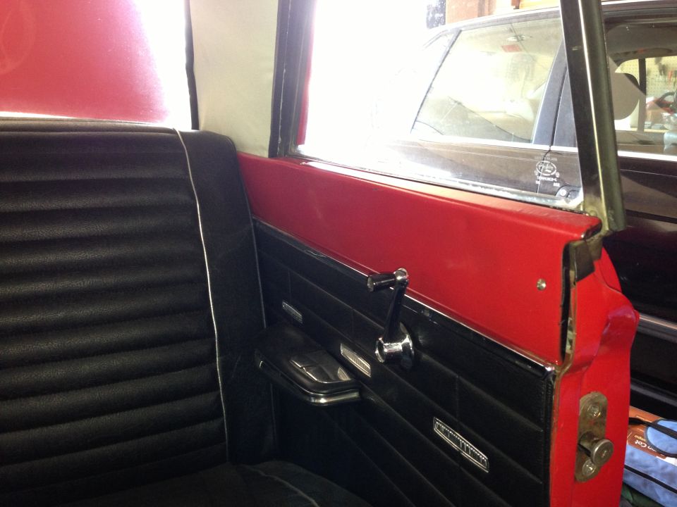 Interior shot of a car's back seat and door panel. Another car is visible through the window