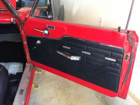 1964 Ford Fairlane - The interior door panel of a classic car, a black textured insert and chrome accents.