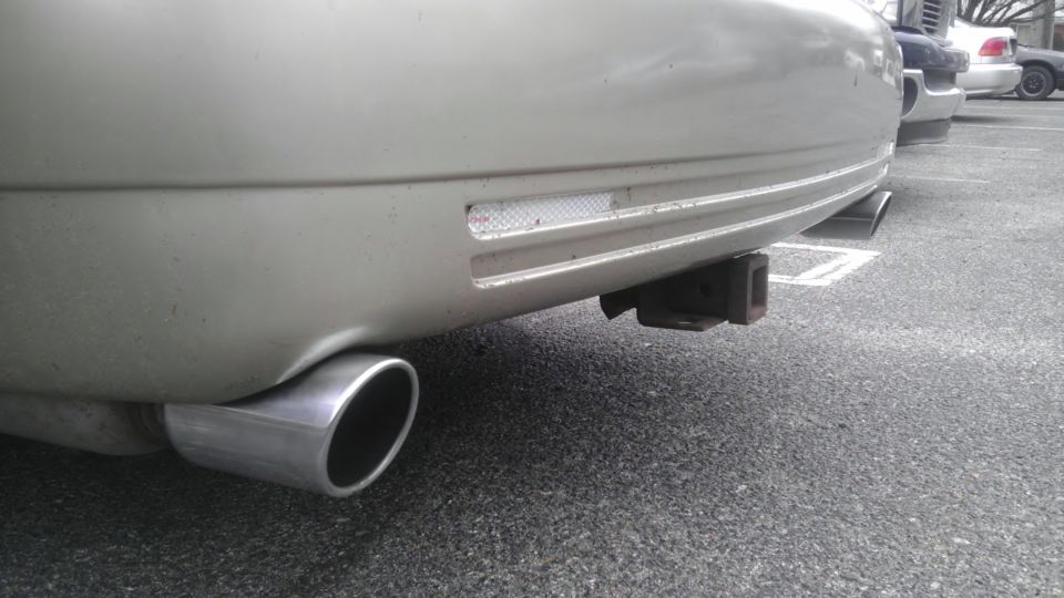 Silver Mercury Grand Marquis rear bumper with dual exhaust pipes and a trailer hitch