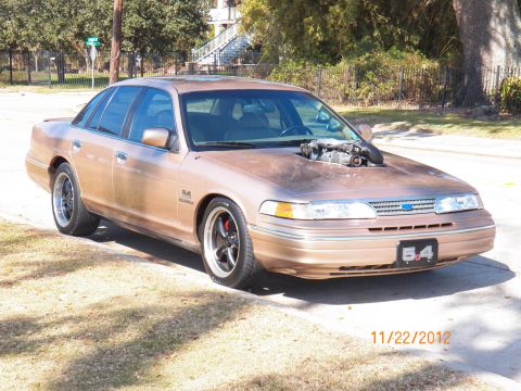 1993 Ford Crown Victoria - This heavily modified Ford sedan features an exposed engine and custom wheels, suggesting it's not a standard 1993 model.
