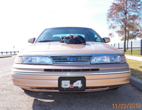 1993 Ford Crown Victoria - This modified Ford Crown Victoria features a prominent engine intake and a custom license plate indicating '5.4'.