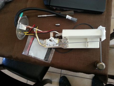 1994 Ford Bronco - A disassembled fuel pump assembly lies on a table, showing its internal components and wiring.