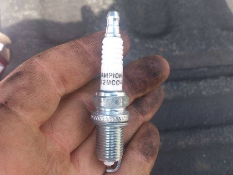2004 Dodge 1500 - A Champion spark plug, model 12MCC4, is held in a hand with visible dirt and grease.