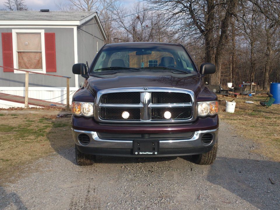Maroon Dodge Ram pickup truck, front view, parked on gravel driveway