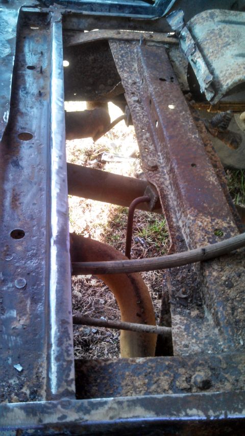 1979 Ford Bronco - The undercarriage of a vehicle shows significant rust on the frame and exhaust system.