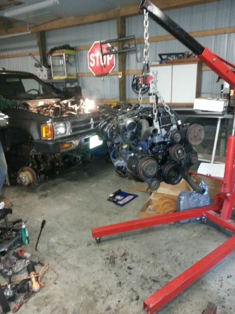 1987 Toyota 4Runner - Engine removal in progress inside a garage with tools and equipment scattered around.