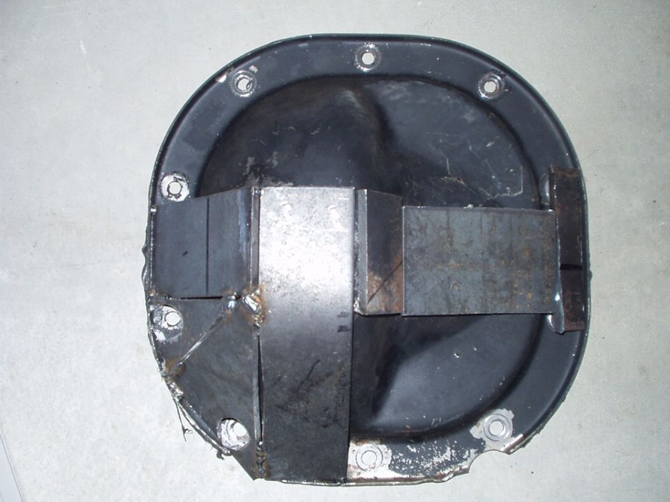 Black differential cover with welded steel gusset reinforcement plates on concrete floor