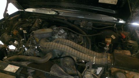 1994 Ford Bronco - The engine bay of a vehicle is shown with various mechanical parts and wiring. A watermark indicates the source as Supermotors.net.
