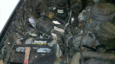 1994 Ford Bronco - The engine bay of a vehicle, a DieHard battery and various engine parts.