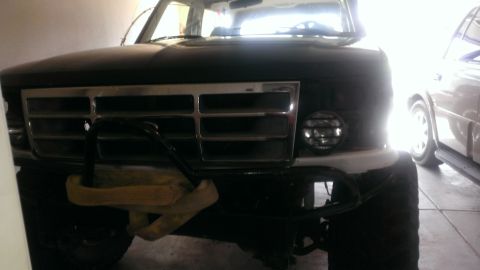 1994 Ford Bronco - Frontal view of a dark SUV, possibly a 1992 model, with a chrome grille and a tow strap attached.