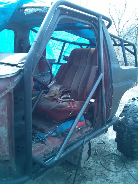 1986 Ford Bronco - Interior view of a heavily modified 1980s Ford Bronco, showing custom roll cage and red seats.