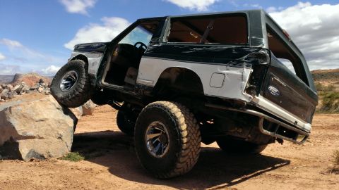 1994 Ford Bronco - This modified Ford Bronco is navigating a rocky obstacle course with one wheel elevated.