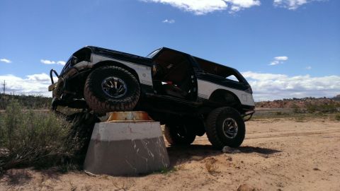 1994 Ford Bronco - Modified 1994 Ford Bronco positioned on a concrete structure in a desert landscape.