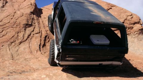 1994 Ford Bronco - A black Ford Bronco navigates a steep rocky incline, viewed from the rear.