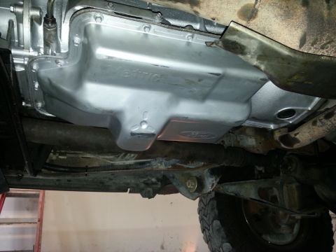 1994 Ford Bronco - The transmission pan of a vehicle, showing a Ford logo and some exhaust components.