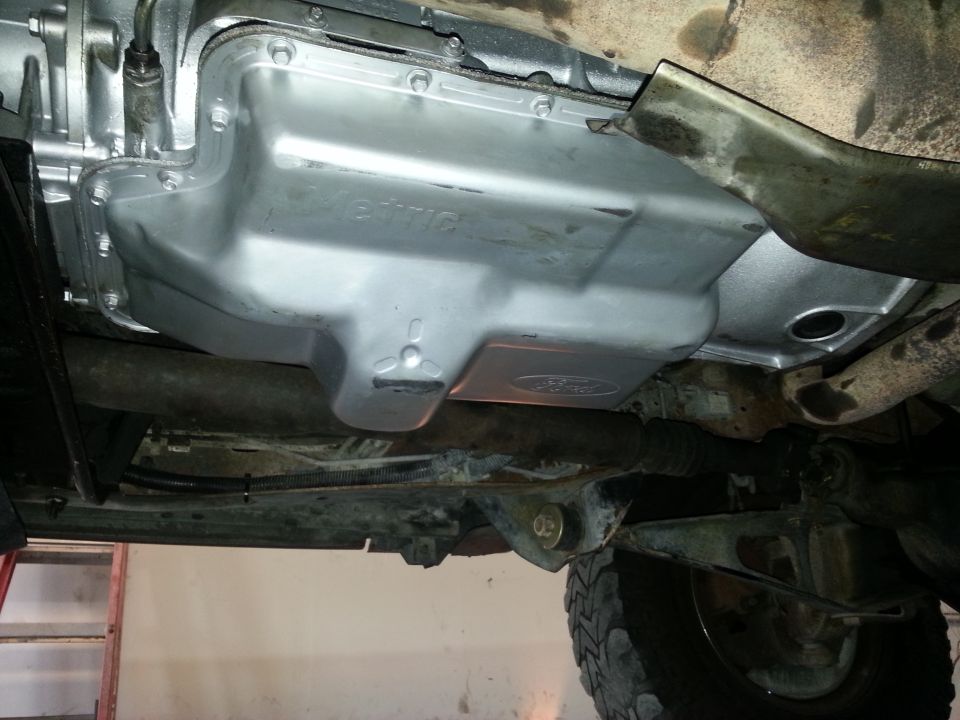 Underside view of a vehicle's transmission pan, which has a Ford logo on it