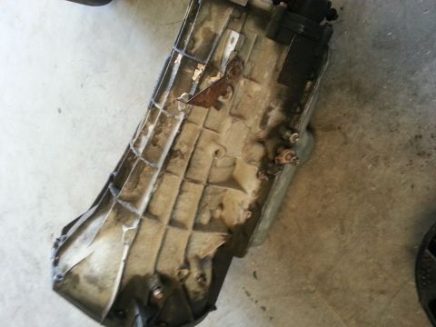 1994 Ford Bronco - A close-up view of a dirty and slightly rusted transmission housing, likely removed from a vehicle.