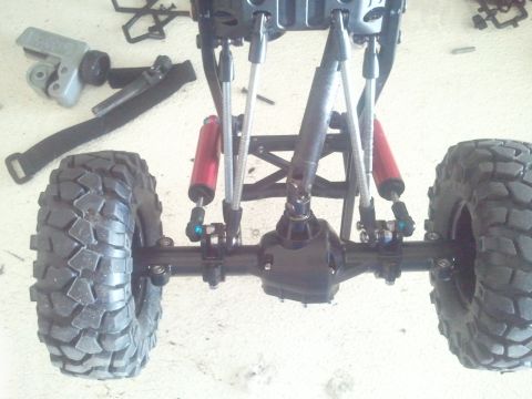 1985 Ford Bronco - Close-up of a remote control car's rear suspension and large off-road tires.