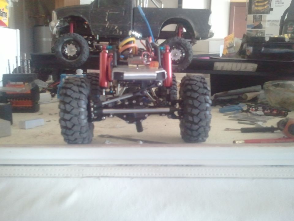 RC truck chassis with red shocks and large knobby tires, viewed from the front