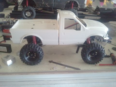 1985 Ford Bronco - This is a side view of a white RC truck model that is still under construction, with another RC vehicle visible behind it.
