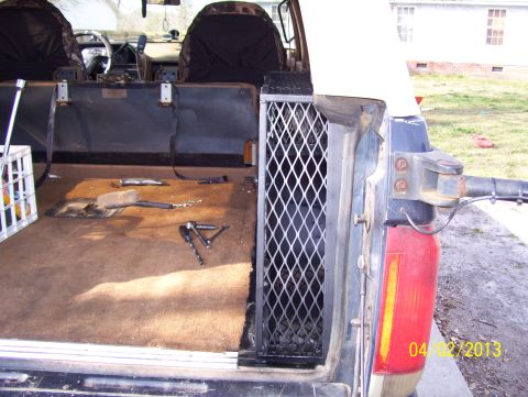 1990 Ford Bronco - Rear storage area of a 1990 Ford Bronco, showing tools and a metal grate.