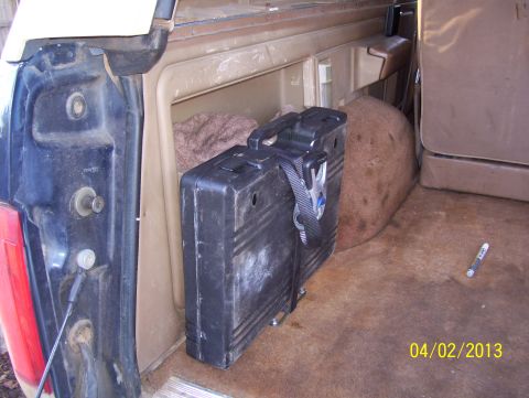 1990 Ford Bronco - The interior of a 1990 Ford Bronco shows the rear storage area with a black case and brown carpet.