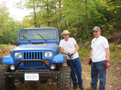 1990 Ford Bronco - A blue Jeep Wrangler is parked on a dirt path with two men standing beside it.