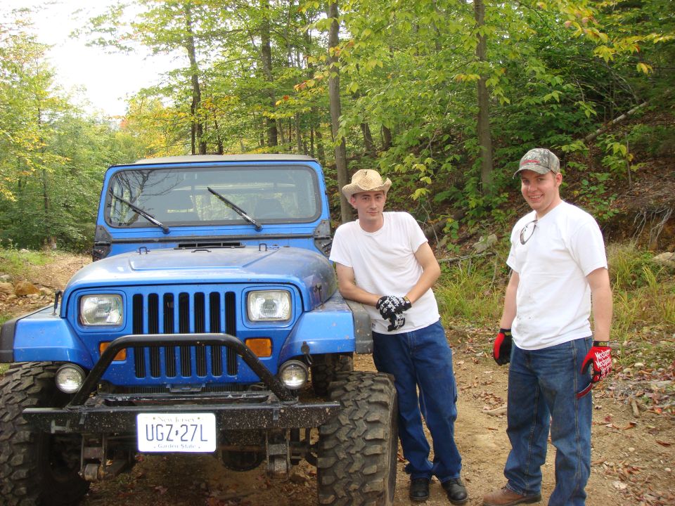 Blue Jeep Wrangler with two men standing next to it