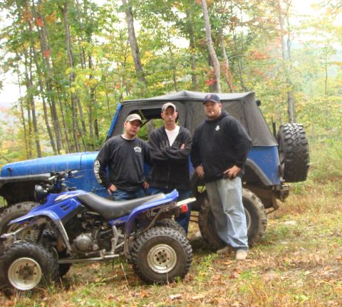 1990 Ford Bronco - Three men pose with a blue ATV and a blue Jeep Wrangler in a forest setting.