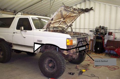 1988 Ford Bronco - A white 1988 Ford Bronco is shown in a garage with its hood open, revealing the engine bay and a custom bumper with a winch fairlead.