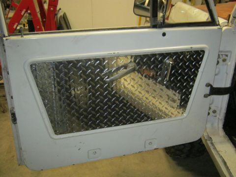 1970 Ford Bronco - Close-up of a vehicle's interior door panel, diamond plate accents and hardware.