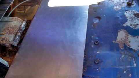 1979 Ford Bronco - A rusted blue metal panel shows signs of repair with a new sheet metal patch.